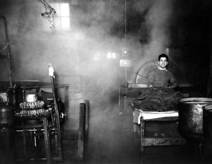 A worker on the assembly line of a Connecticut hat manufacturing plant. is working with colorizing agents as he produces felt hats. Note that the man is not wearing a protective breathing mask, gloves, or goggles. Working as he was with steam, and processed animal fur, airborne remnants of mercury nitrate could have easily been liberated, which he would then readily inhale. Inhalation of airborne mecury componds would have eventually lead to neurologic pathology, due to toxic heavy metal mercurialism. The image was published in the ”Public Health Bulletin”, No. 263, 1941, in an article entitled, ”Mercurialism and its Control in the Felt-Hat Industry". Photo: National Institute for Occupational Safety and Health (NIOSH)